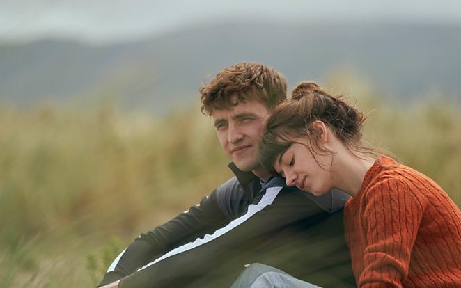 Connell and Marianne from Normal People sit together in a field. 