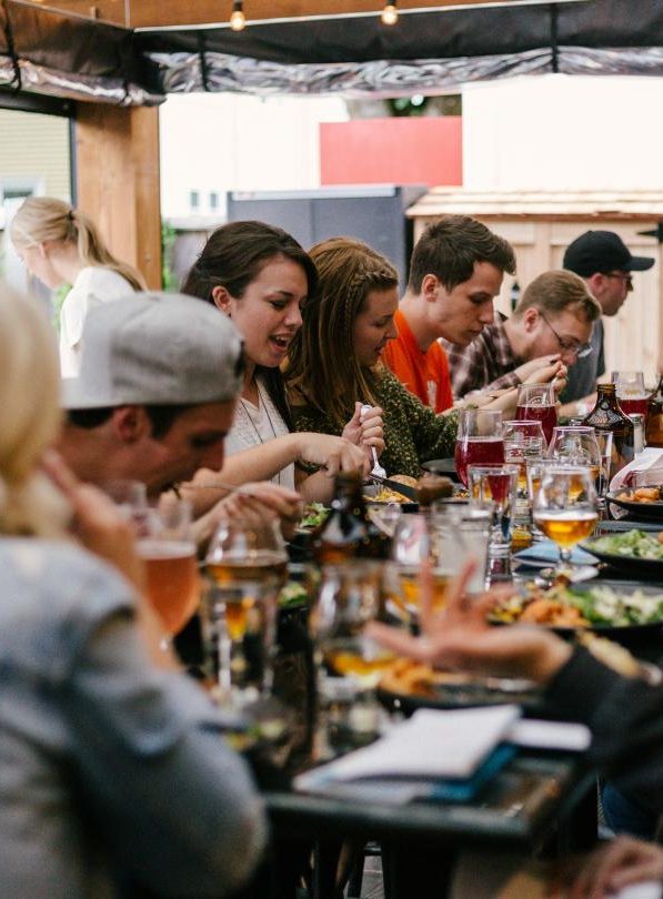 A group of young gen z twentysomethings eat food at a supper club in London.