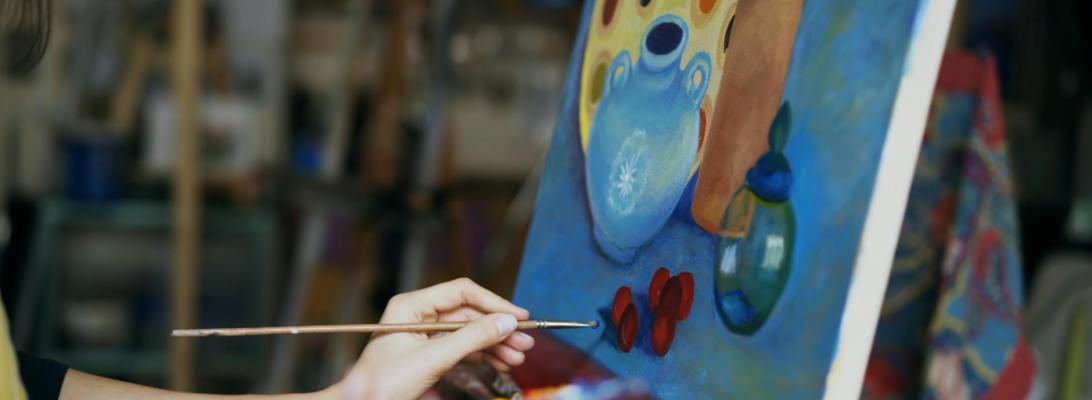 A woman painting a picture as a way to find healing through the arts and creativity.
