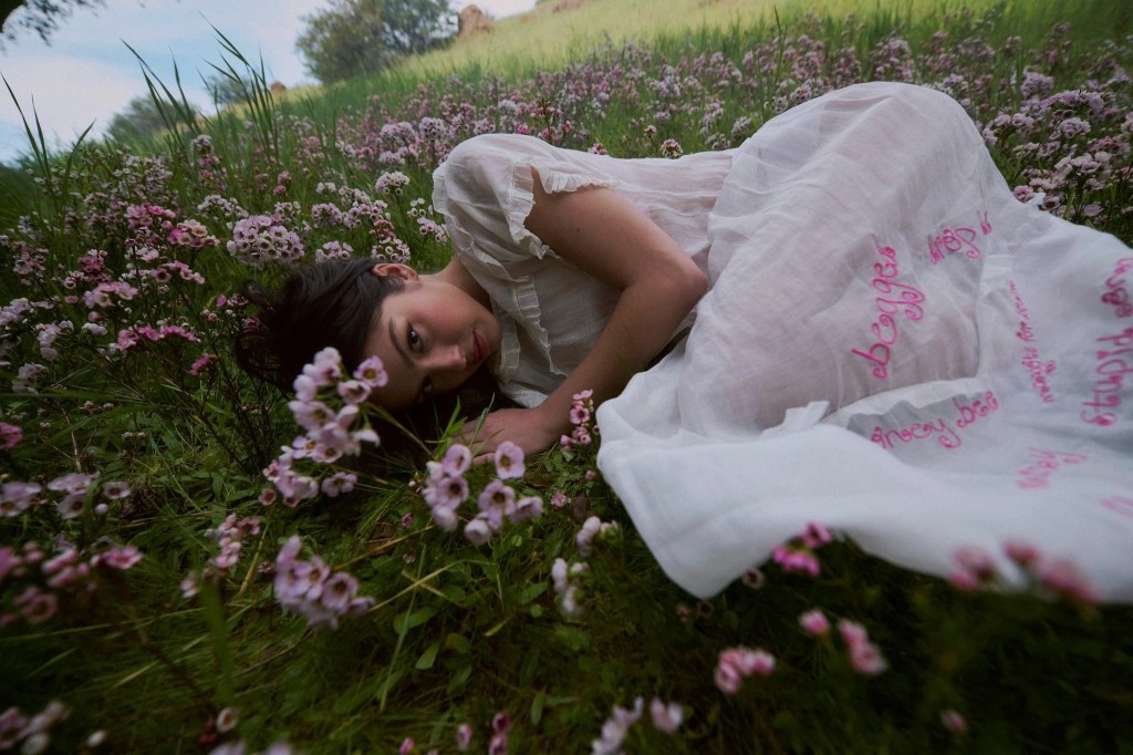 Olivia Rodrigo lying in a field of flowers in an image from her album you seem pretty sad for a girl so in love.